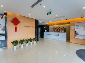 En hotellobby med modern design, inklusive en receptionsdisk, krukväxter och en skylt som är monterad på väggen.