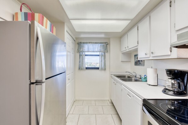 A compact kitchen with a refrigerator, stove, sink, and cabinets. - Shoreline view for miles- Oceanfront heated pool (Cape Canaveral)