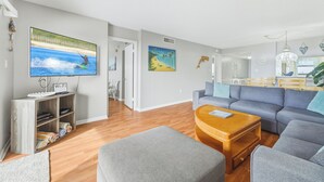 Ett modernt vardagsrum med en grå soffa, ett träbord och en platt-TV som är monterad på väggen.
