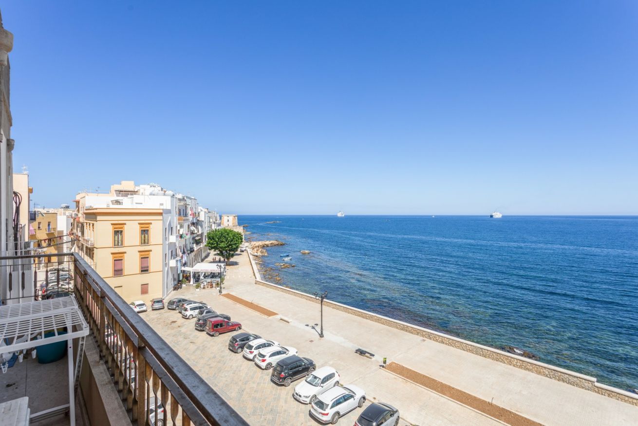 Eine Küstenstraße mit geparkten Autos, blauem Himmel und Blick auf das Meer.