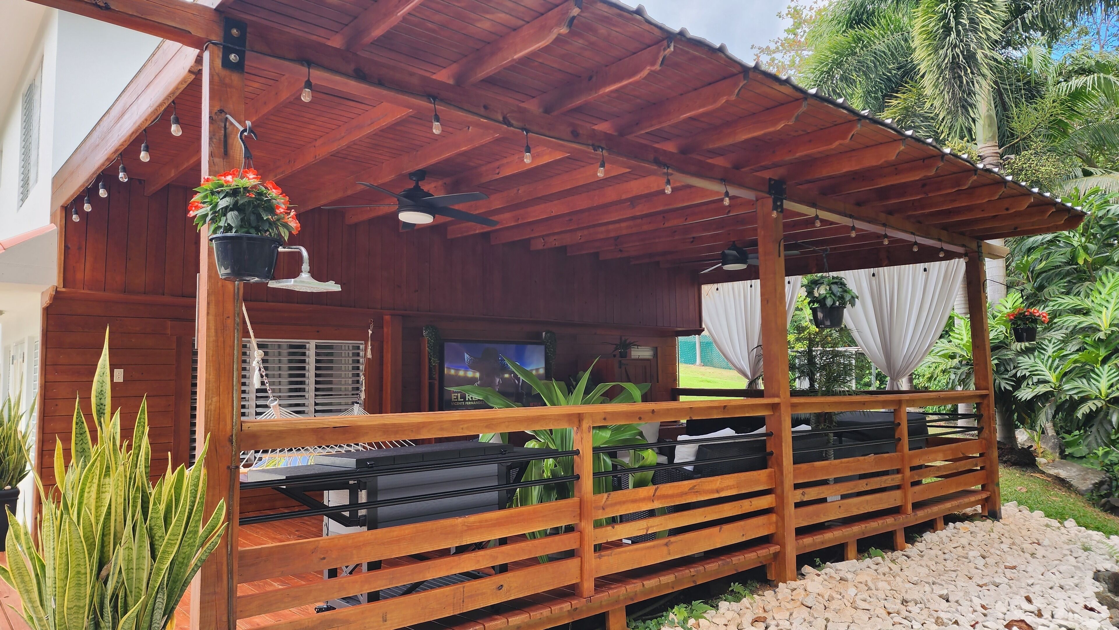 A covered outdoor seating area with wooden benches and hanging plants.