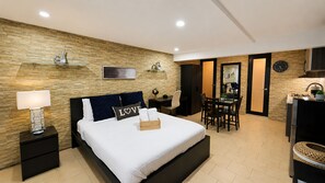 A modern hotel room with a bed, bedside table, lamp, and a small desk with a chair. - Palm's Luxury Suite with Jacuzzi (Aguada)