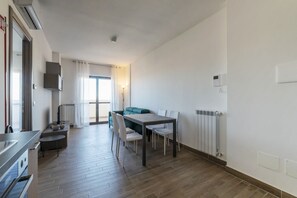 A modern kitchen with a dining area, a sofa, and a radiator.