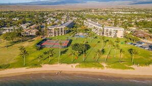 An aerial view of a resort with a beach, a tennis court, and multiple buildings. -  OCEAN FRONT: spacious, remodeled 4th floor condo (Kihei)