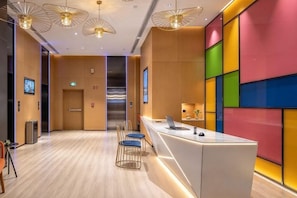 A modern hotel lobby with a reception desk, seating area, and a staircase. - Sofis Pop Hotel (Fuzhou)