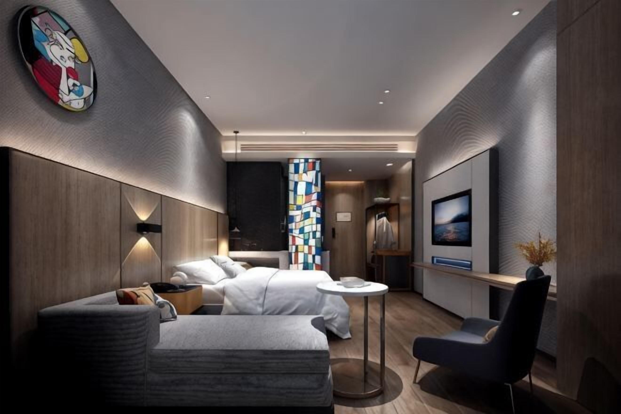 A modern hotel room with a sofa, two beds, a TV, and a small table.