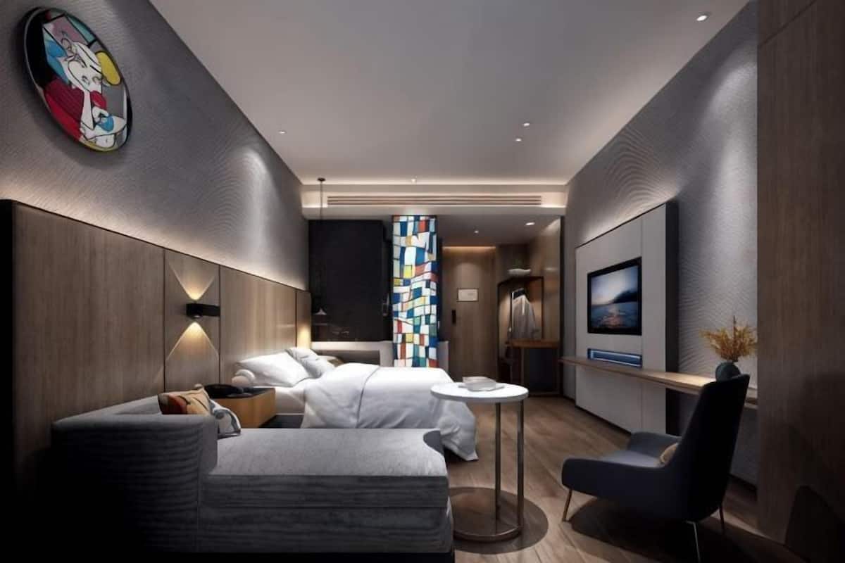 Una habitación de hotel moderna con sofá, dos camas, televisor y una mesita.