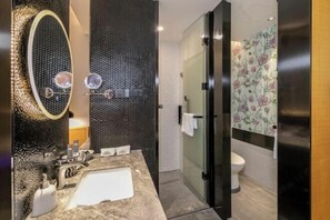 A modern bathroom with a marble sink, a large mirror, a glass shower enclosure, and a toilet with floral wallpaper. - Sofis POP Hotel (Fuzhou)