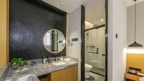 A modern bathroom with a marble countertop, a round mirror, and a glass shower enclosure. - Sofis POP Hotel (Fuzhou)