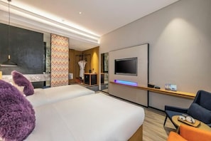 A hotel room with a bed, a TV, a seating area, and a mirror. - Sofis Pop Hotel (Fuzhou)