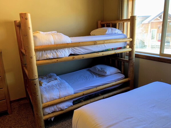 Una cama litera con ropa de cama blanca en una habitación con ventana.