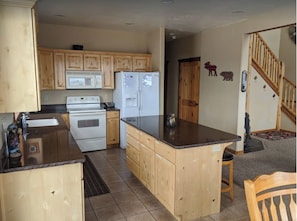Cocina compacta con armarios de madera, estufa, refrigerador y encimera de granito.