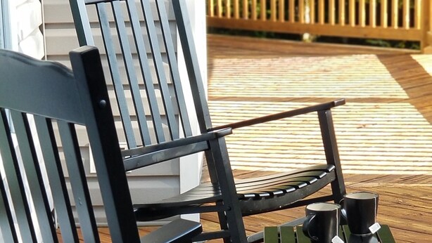 Deux fauteuils à bascule sur une terrasse en bois, avec une clôture en bois en arrière-plan.