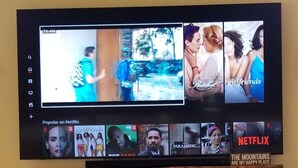 Un téléviseur à écran plat fixé au-dessus d’une cheminée en pierre, diffusant plusieurs émissions de Netflix.