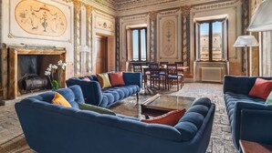 Ein luxuriöses Zimmer mit blauer Sofagarnitur, Kamin und aufwendigen Deckenverzierungen.