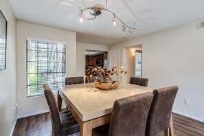 A dining area with a large table, six chairs, and a decorative centerpiece. - Luxury Ventana Canyon Condo + Pools + Spas + Hiking + Golf + Sabino Canyon! (Tucson)