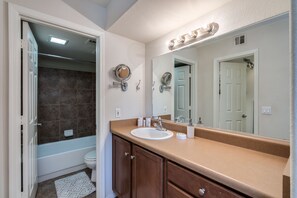A bathroom with a white sink, vanity, and mirror. There is a shower area with a glass door and a towel rack. - Luxury Ventana Canyon Condo + Pools + Spas + Hiking + Golf + Sabino Canyon! (Tucson)
