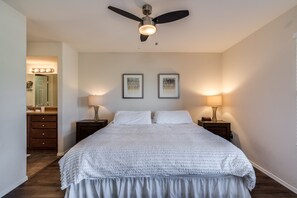 A bedroom with a large bed, two bedside tables with lamps, a ceiling fan, and two framed pictures on the wall. - Luxury Ventana Canyon Condo + Pools + Spas + Hiking + Golf + Sabino Canyon! (Tucson)
