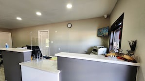 A reception area with a reception desk, a clock on the wall, and a mounted television.