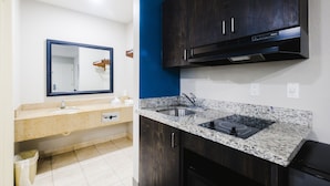 A modern kitchen with dark wooden cabinets, a granite countertop, and a built-in stove.