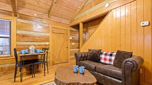 Un intérieur en bois avec un canapé en cuir marron, une table à manger en bois et des chaises, ainsi qu’une table basse ronde.