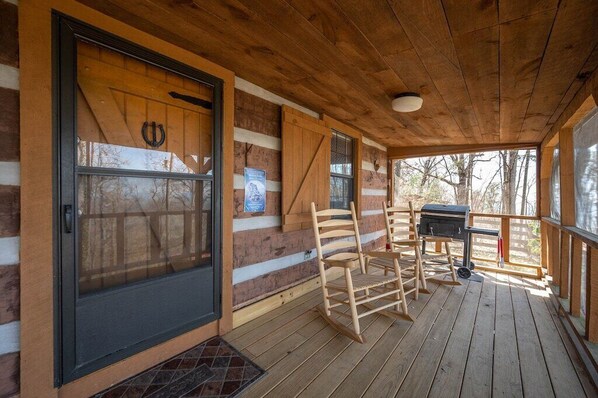Une terrasse en bois avec un porche couvert, une porte-fenêtre coulissante et un espace barbecue.