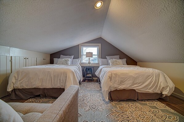 A bedroom with two beds, a window, and a patterned rug. - Creekside Cottages Luxury King/The Nook (Blairsville)