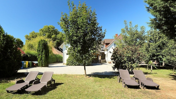 Ein Garten mit Liegestühlen, einem Kiesweg und einem Gebäude im Hintergrund.