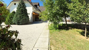 Ein Wohnhaus mit Kopfsteinpflasterauffahrt, einer überdachten Veranda und einem großen Nadelbaum.