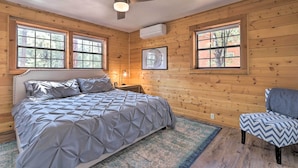 Een slaapkamer met een bed, een stoel, een plafondventilator en grote ramen.