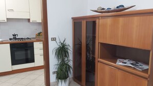 Una cocina moderna con armarios blancos, una estufa a gas y una planta en maceta.