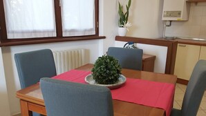 Un comedor con una mesa de madera, sillas azules, un mantel rojo y una planta en maceta.