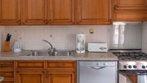 Une cuisine avec des meubles en bois, un évier en acier inoxydable, une machine à café, un grille-pain et un lave-vaisselle.