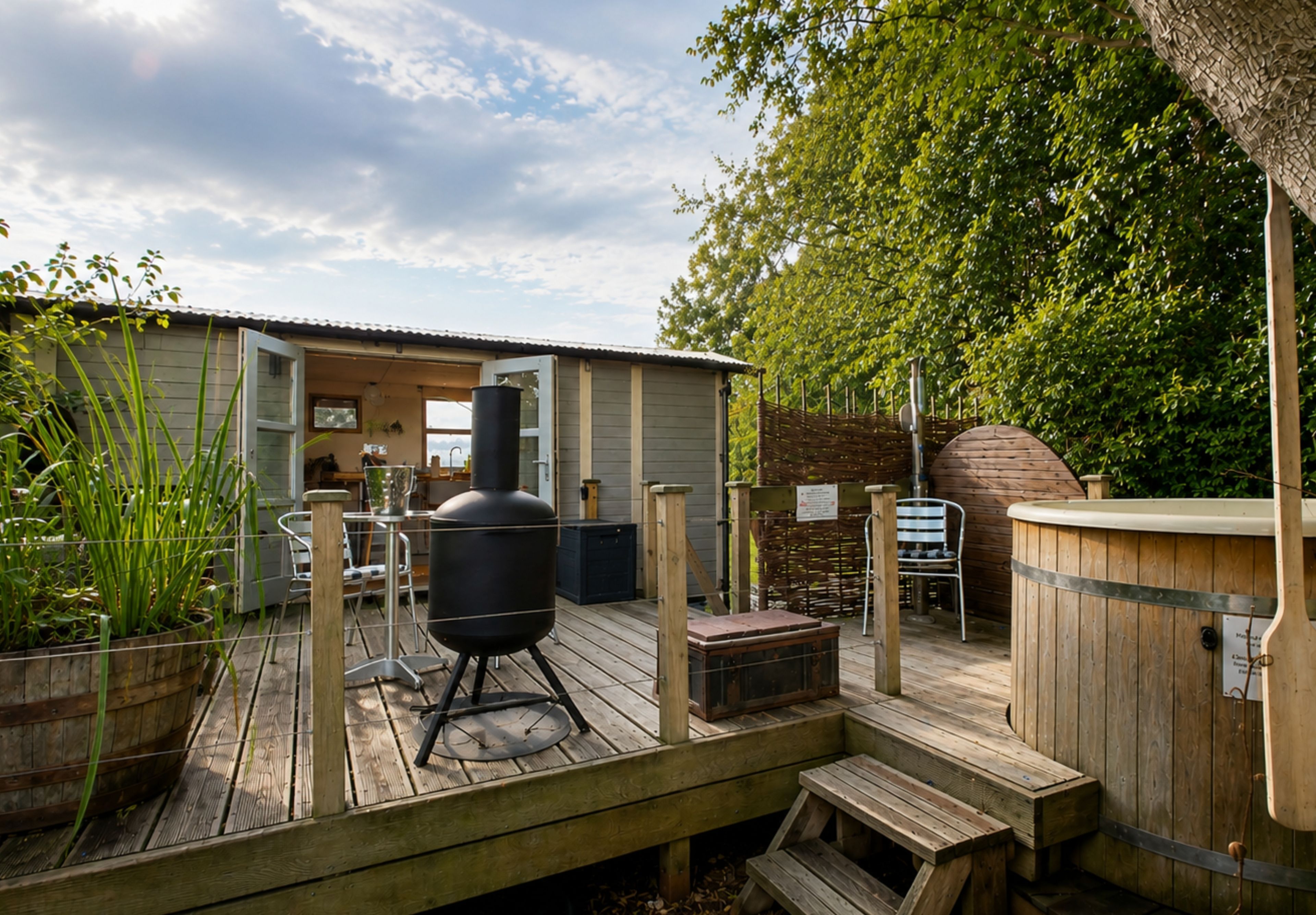 Eine Holzterrasse mit Grill, Whirlpool und Sitzgelegenheit im Freien.