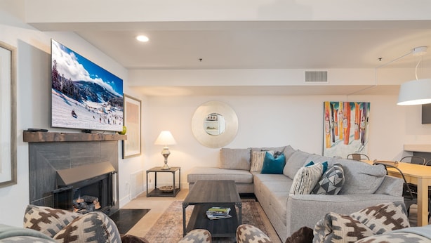 A modern living room with a fireplace, a sofa, a coffee table, and a television mounted on the wall. - Ski in Ski out with a view. Fantastic 2 bed condo. (Park City)