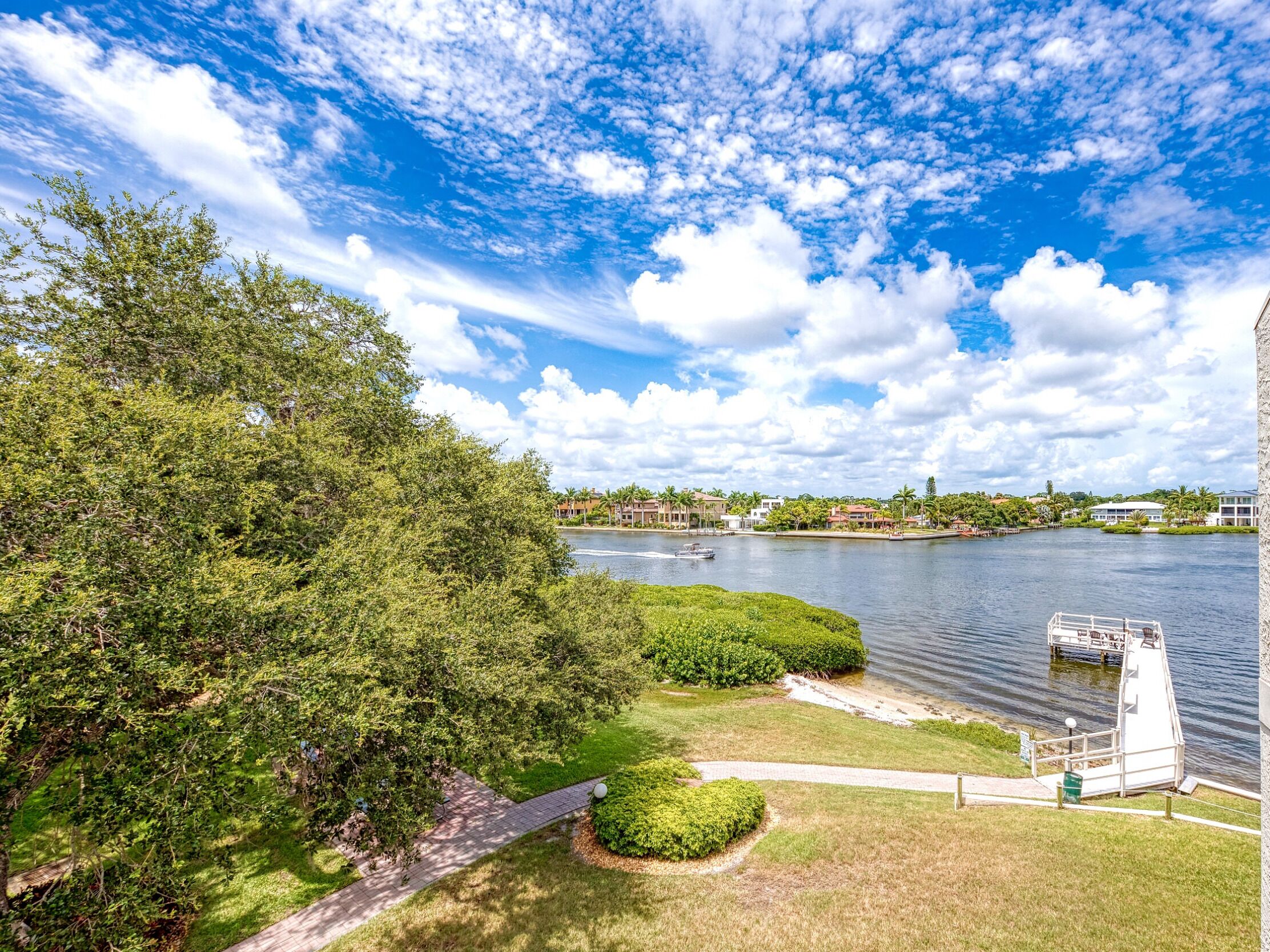 A riverside view with a dock, lush greenery, and a clear sky.