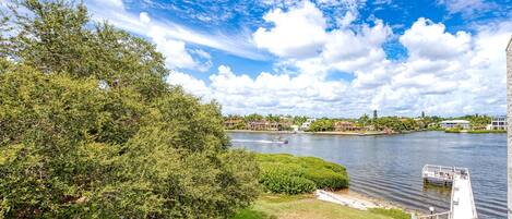 A riverside view with a dock, lush greenery, and a clear sky.