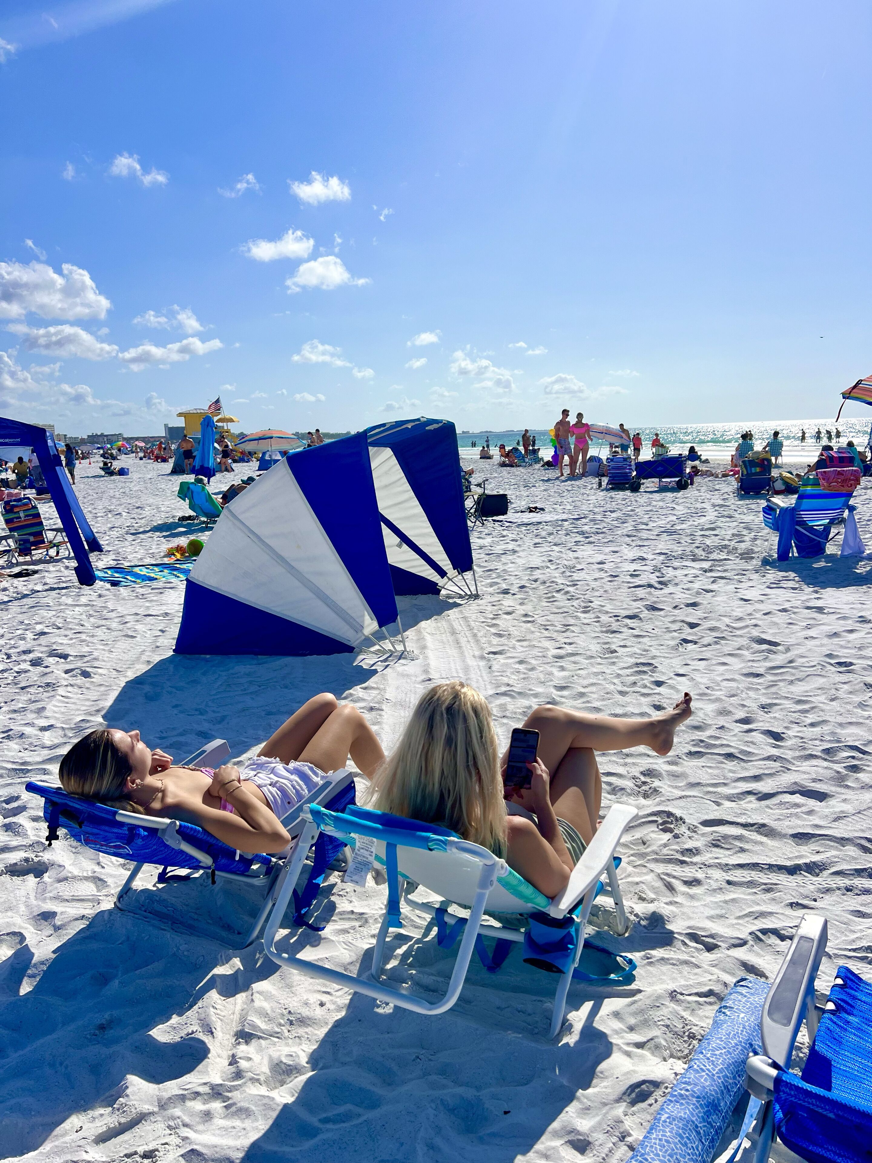 A beach with people relaxing on sun loungers and umbrellas.