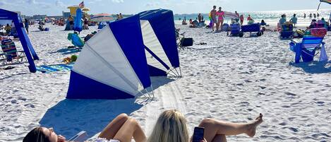 A beach with people relaxing on sun loungers and umbrellas.