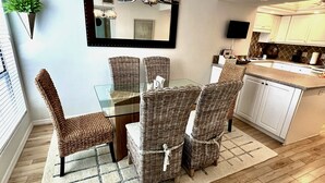 A dining area with wicker chairs, a glass table, and a chandelier. - Luxury Waterfront Views / Pool / 1400sf / Minutes to Beach (Siesta Key)
