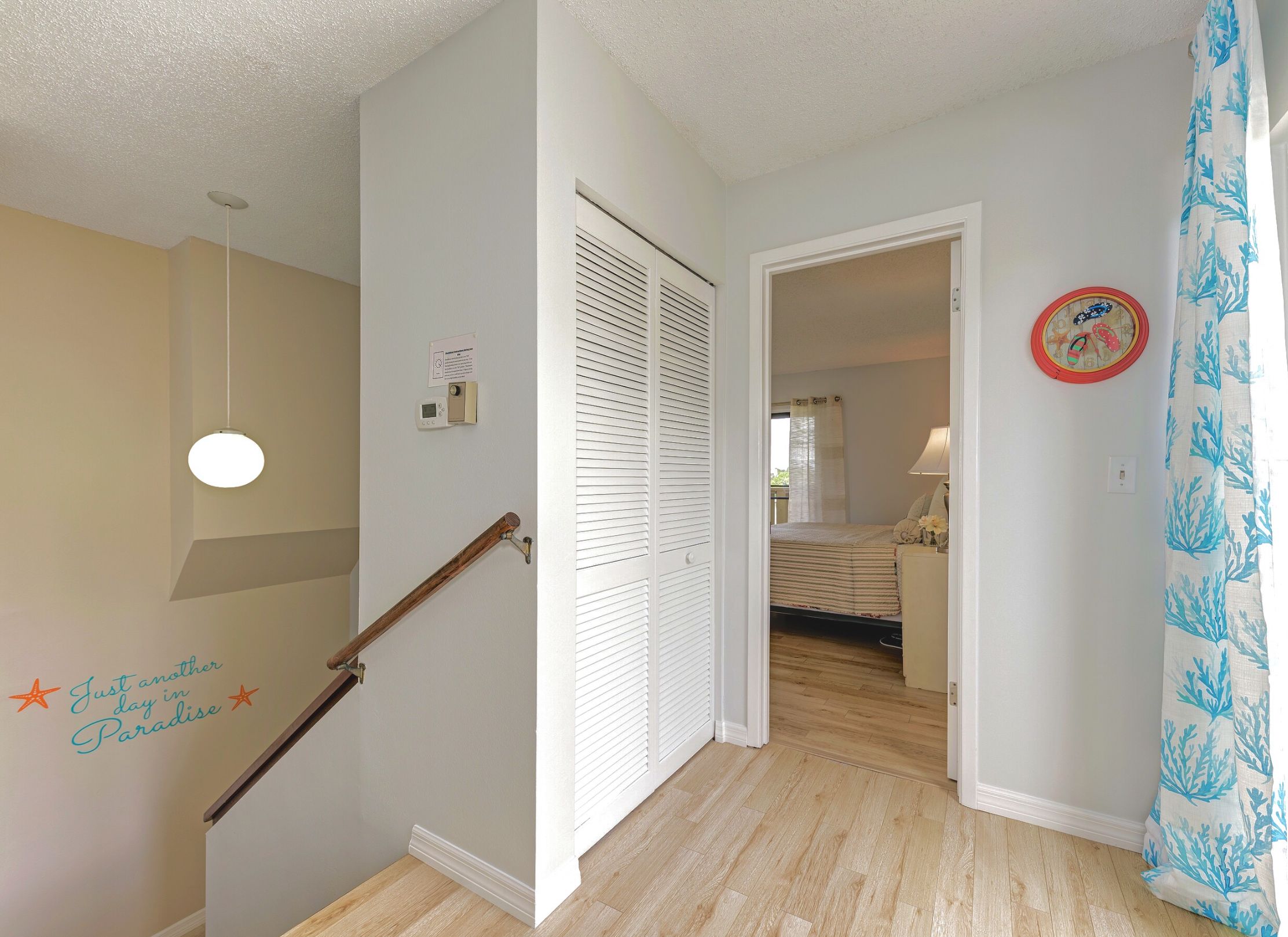 A staircase with a handrail, a wall-mounted light, a thermostat, and a sign.