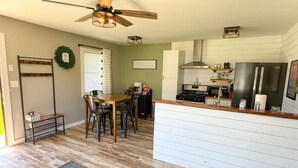 A modern kitchen with a built-in stove, microwave, and refrigerator. There is a dining area with a wooden table and chairs.