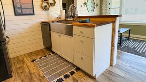 A compact kitchen with a wooden countertop, a built-in sink, and a small window.