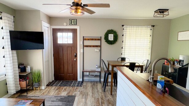 A compact kitchen with a wooden countertop, a ceiling fan, and a dining area with a table and chairs.