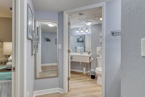 A hallway leading to a bathroom with a sink, mirror, and toilet. - HS-1127 Ocean View Condo in Myrtle Beach - 1 Bedroom, Sleeps 6 (Myrtle Beach)