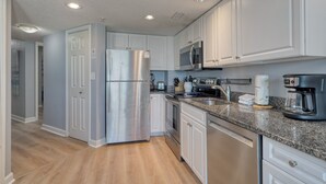 Una cocina moderna con armarios blancos, electrodomésticos de acero inoxidable y encimeras de granito.