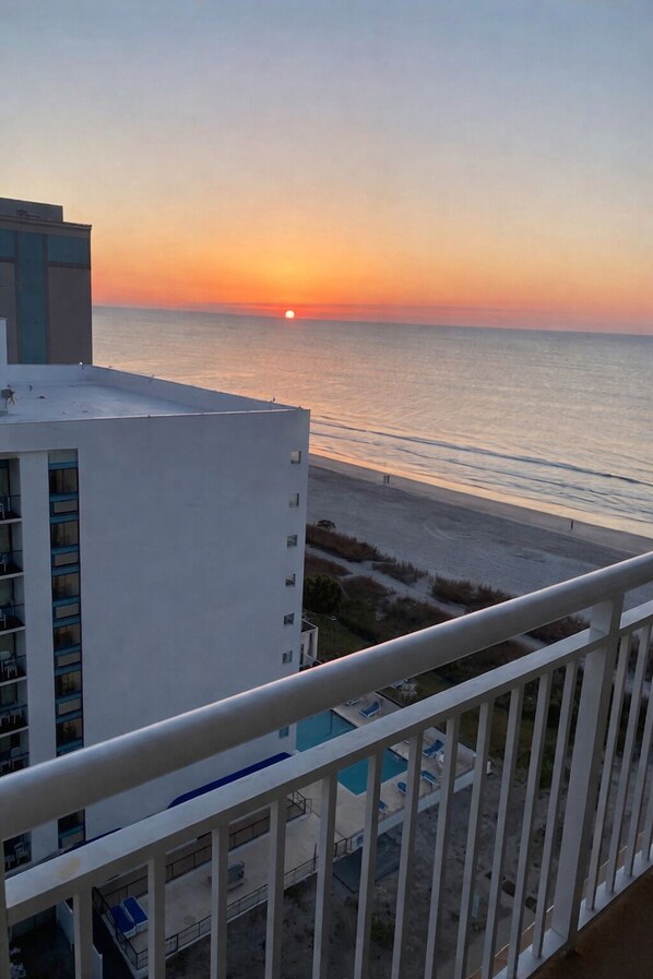 A high-rise building with a view of the sunset over the ocean, a balcony with a railing, and a pool area. - HS-1127 Ocean View Condo in Myrtle Beach - 1 Bedroom, Sleeps 6 (Myrtle Beach)
