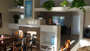 A dining area with a table and chairs, a water dispenser, and a Buddha statue on a shelf. - 3 bedroom house w/Private Pool, Spa&Golf Course! (La Quinta)