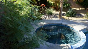 A swimming pool surrounded by lush greenery and a stone wall. - 3 bedroom house w/Private Pool, Spa&Golf Course! (La Quinta)