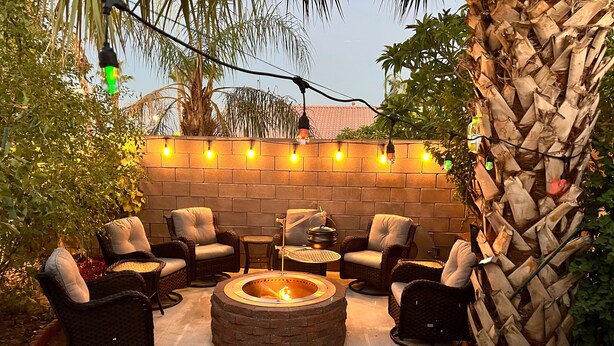 An outdoor seating area with wicker chairs, a fire pit, and string lights. - 3 bedroom house w/Private Pool, Spa&Golf Course! (La Quinta)